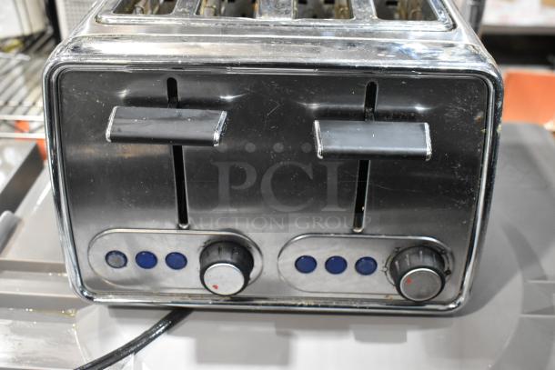 Vintage stainless steel toaster with dual slots, two levers, and control knobs. Scratches and wear visible. No brand markings.