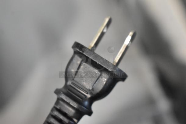 Black two-prong electrical plug, close-up, in good condition. Basic design, likely standard North American type.