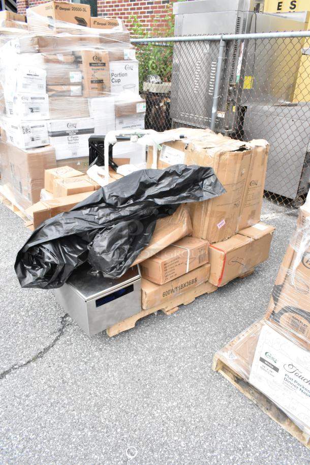 Pallet of assorted boxes and packaging, including Genpak portion cup boxes, partially covered with black plastic. Items appear unopened.
