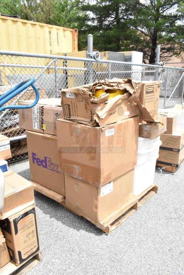 Pallet with various cardboard boxes, some damaged. FedEx label visible. Outdoors near metal fence and yellow container.