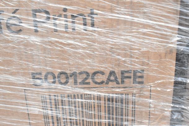 Cardboard box wrapped in plastic, marked with "50012CAFE" and a visible barcode, ready for shipping or storage.