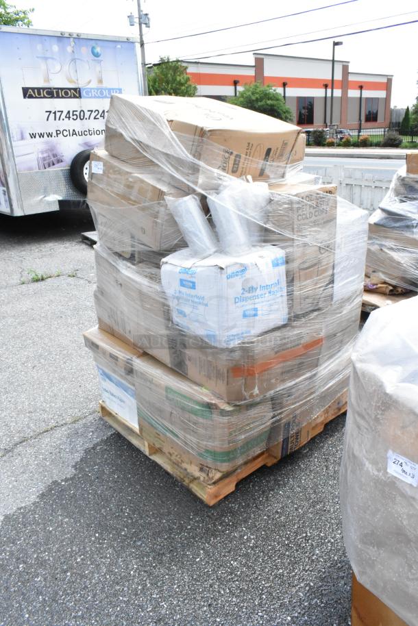 Pallet of assorted boxes wrapped in plastic, containing 2-ply napkins and other items, showing outdoor warehouse setting.