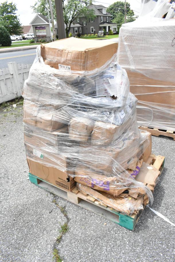 Pallet of mixed cardboard boxes wrapped in plastic, some damaged. Labels indicate fragile contents. Outdoor setting.