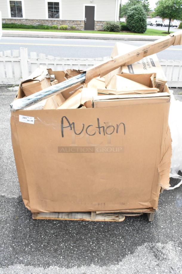 Large cardboard box labeled "Auction" on a wooden pallet, containing assorted items in various conditions. Marked "285 pcs."