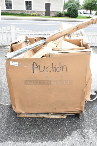 Large cardboard box labeled "Auction" on a wooden pallet, containing assorted items in various conditions. Marked "285 pcs."