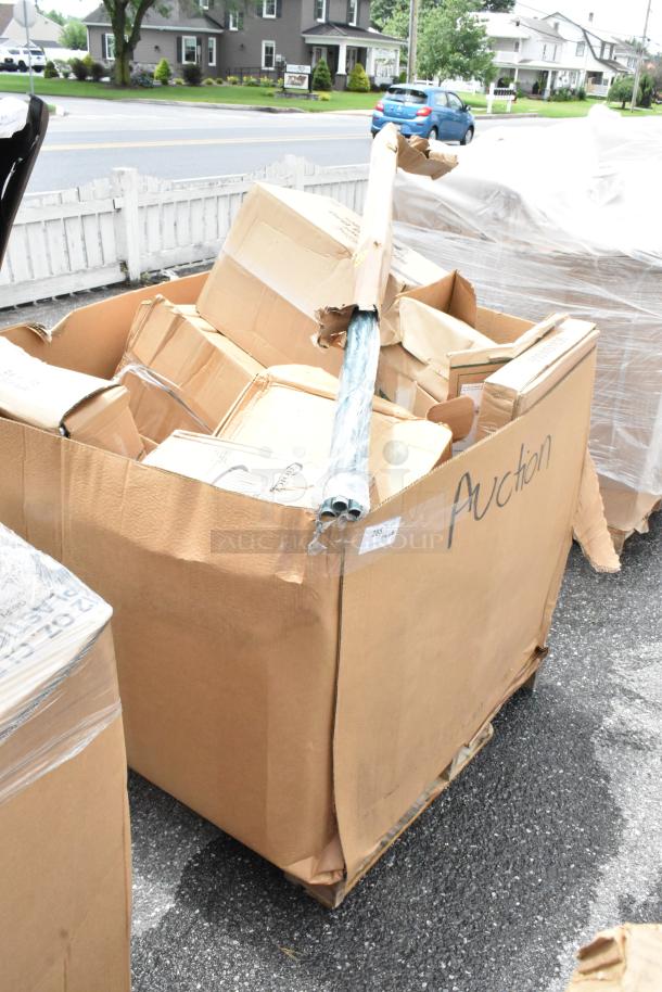 Large cardboard box labeled "Auction" filled with assorted smaller boxes and wrapped pipes. Box appears worn and taped.