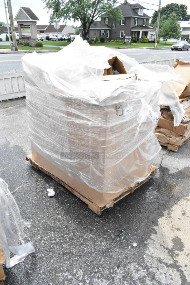 Pallet of goods wrapped in plastic, cardboard boxes visible, stored outdoors. Label with numbers attached. Condition unknown.