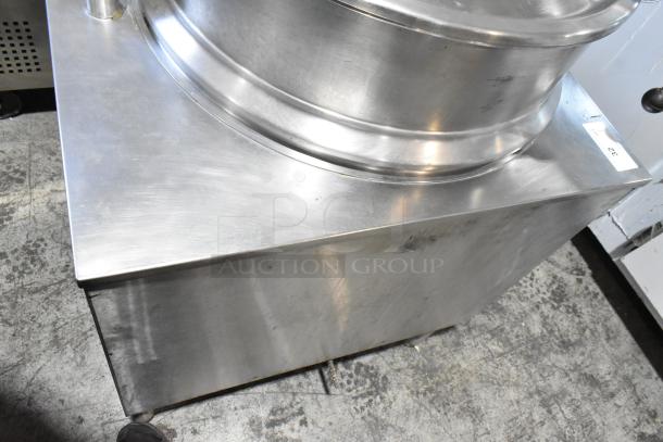 Stainless steel kitchen equipment with a cylindrical top, visible wear, on a metal base. Label marked "32."