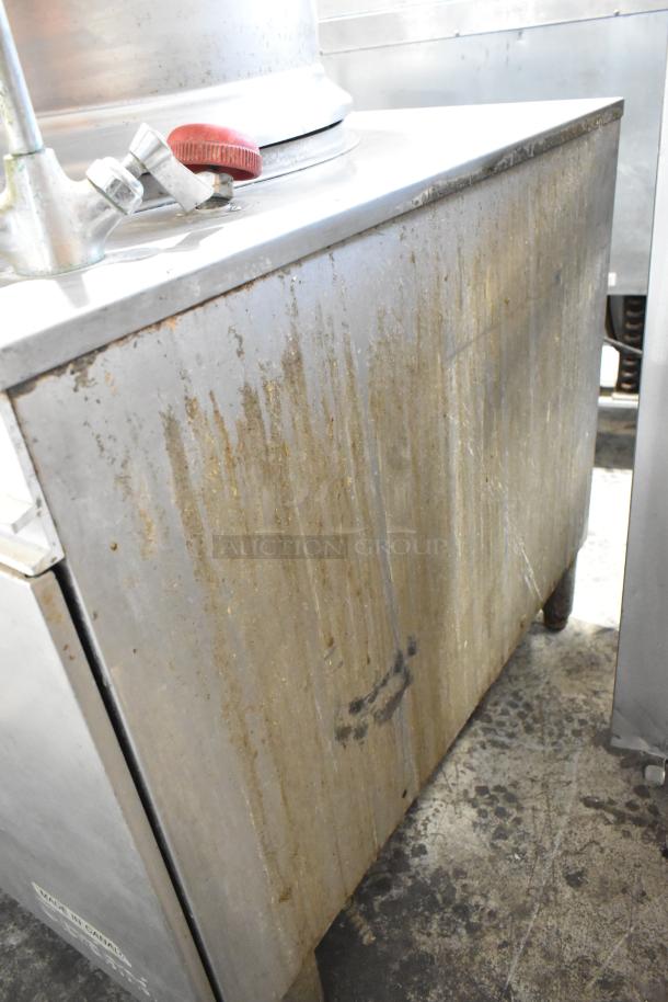 Stainless steel commercial appliance with visible wear and grime. Features a red valve. Marked "Made in Canada."