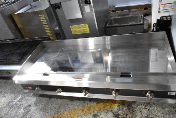 Stainless steel commercial griddle with temperature control knobs, in good condition. Features adjustable heat settings.