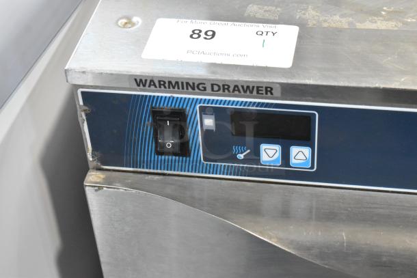 Stainless steel warming drawer with digital controls and on/off switch. Item label "89 QTY 1." Suitable for commercial use.