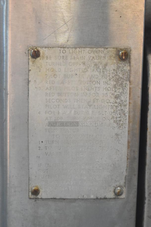 Metal instruction plate with detailed lighting and safety instructions for operating a gas oven; weathered condition.
