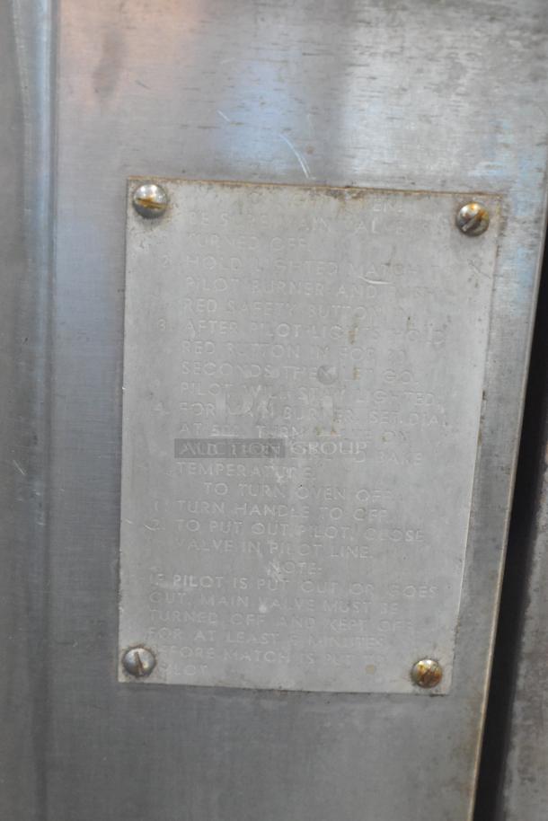 Close-up of a metal plate with engraved text instructions on operating a gas appliance. Slight wear visible.
