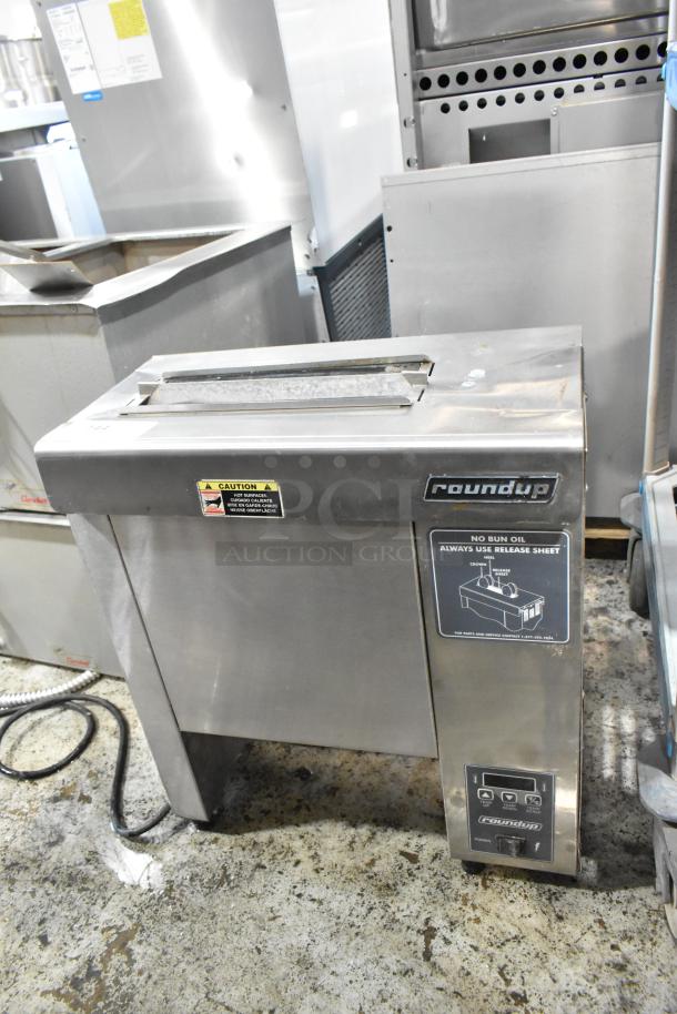 Commercial stainless steel bun toaster by Roundup, features top slot, visible caution label, used condition.