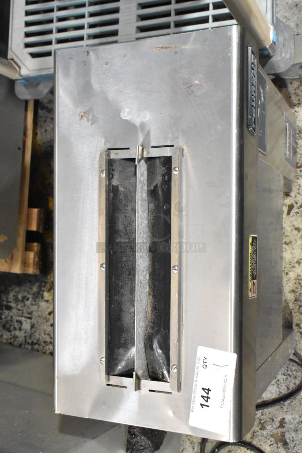 Stainless steel industrial unit with brand logo and caution label. Auction tag "144" attached. Worn and scratched surface.