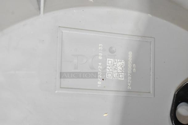 Close-up of a white item with a QR code and numbers "10/23/24 00:33" and "24297596508B 33" indicating identification details.