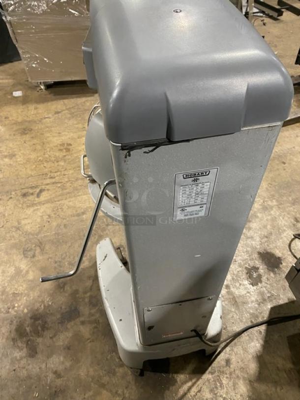 Industrial Hobart commercial mixer, gray, with visible label showing model and power specs, in used condition.