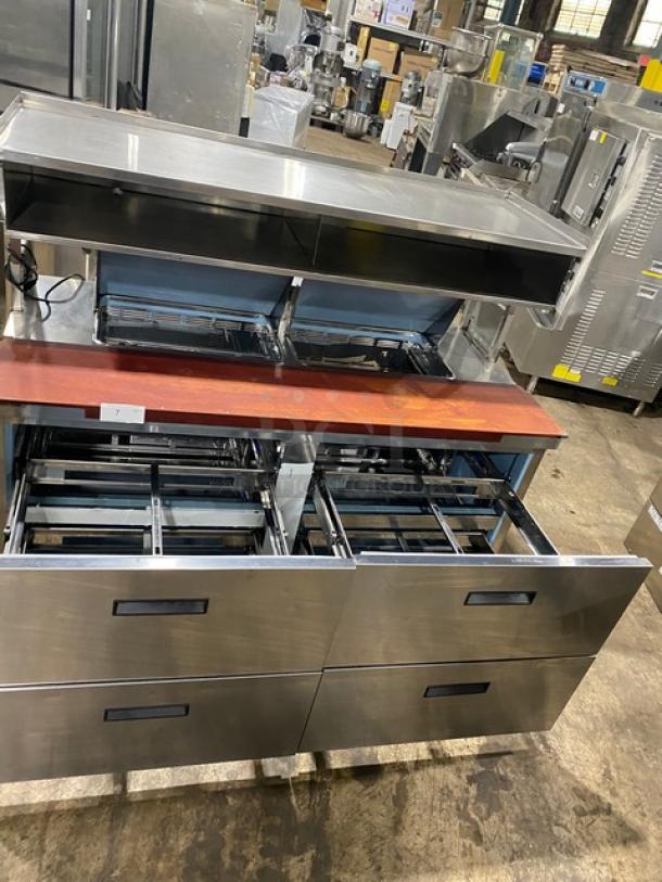 Stainless steel commercial kitchen workstation with drawers and upper shelving. Good condition, suitable for restaurant use.