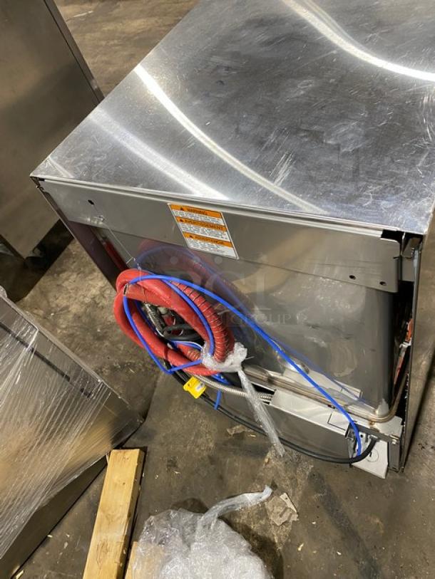 Commercial stainless steel dishwasher, back view showing red and blue cables, minor scuffs. Energy rating label visible.