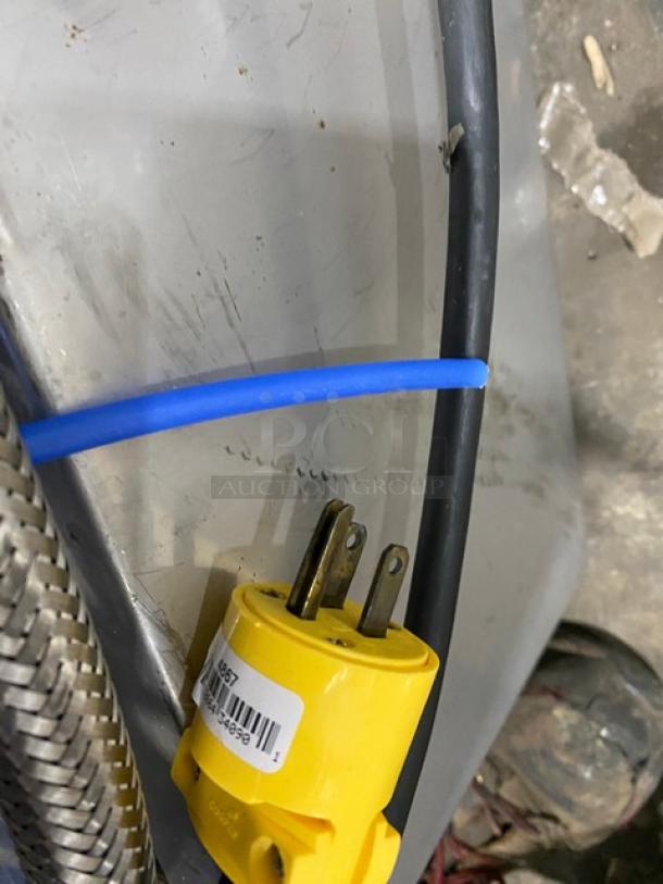 Yellow electrical plug with a barcode label attached, featuring a three-prong design. Shows connected black and blue cables.