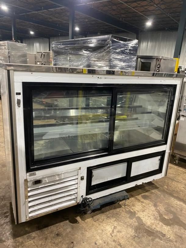 Commercial glass display refrigerator with sliding doors, shelf space, and visible wear. Ideal for showcasing products.
