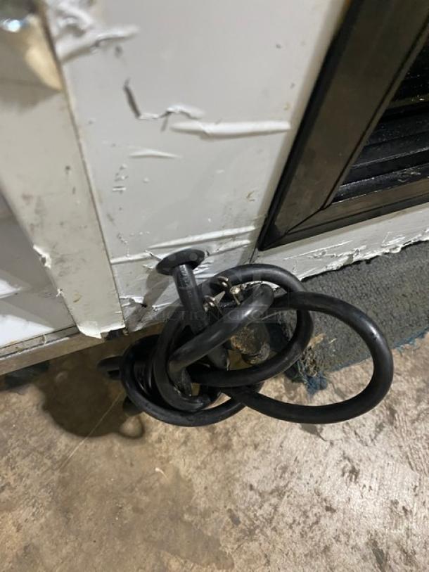 Coiled black cable lock attached to a weathered metal and wood surface.