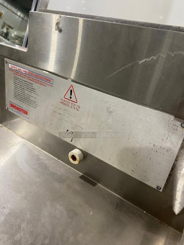 Commercial stainless steel fryer with Broaster branding, visible safety instructions, and handling marks.