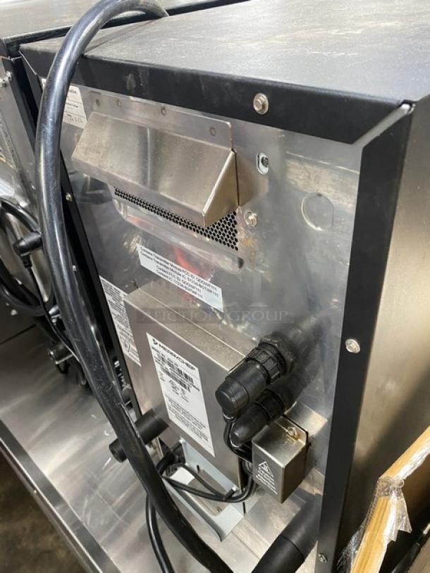 Commercial stainless steel appliance, rear view. Features power cords, control panel, and exhaust vent. Labels indicate specifications and model details. Appears in good condition, suitable for industrial kitchen use.