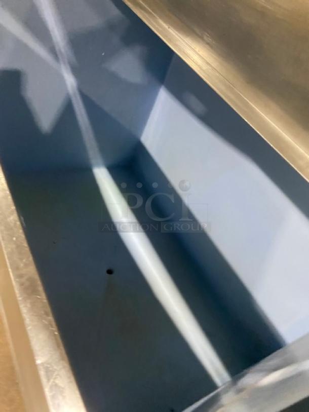 Stainless steel industrial trough, large capacity, blue interior, used condition, no visible markings or labels.