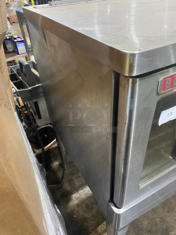 Stainless steel commercial oven with visible wear, brand mark on front panel, suitable for heavy-duty kitchen use.