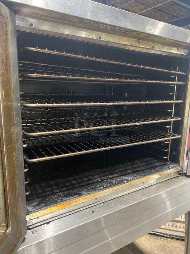 Commercial stainless steel oven with six wire racks, showing signs of use and wear, in operational condition.