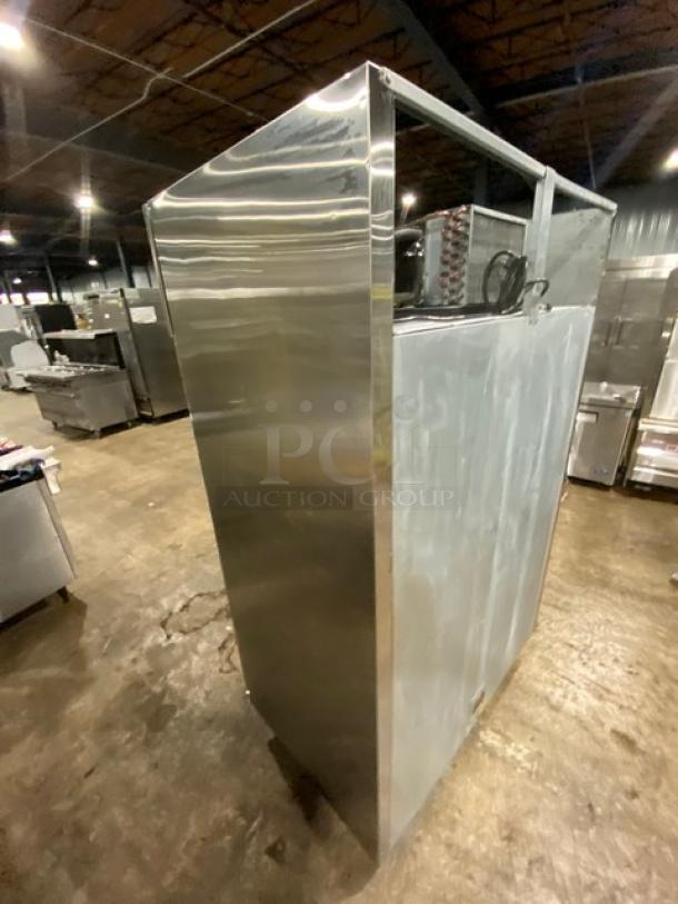 Large industrial stainless steel appliance in warehouse, showing reflective surfaces and metal details. Condition appears used.
