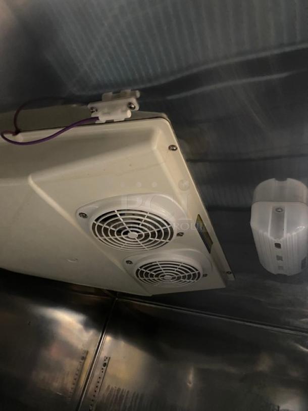 Commercial refrigeration unit fan assembly with dual fans and wiring, mounted in a metal interior. Appears in good condition.