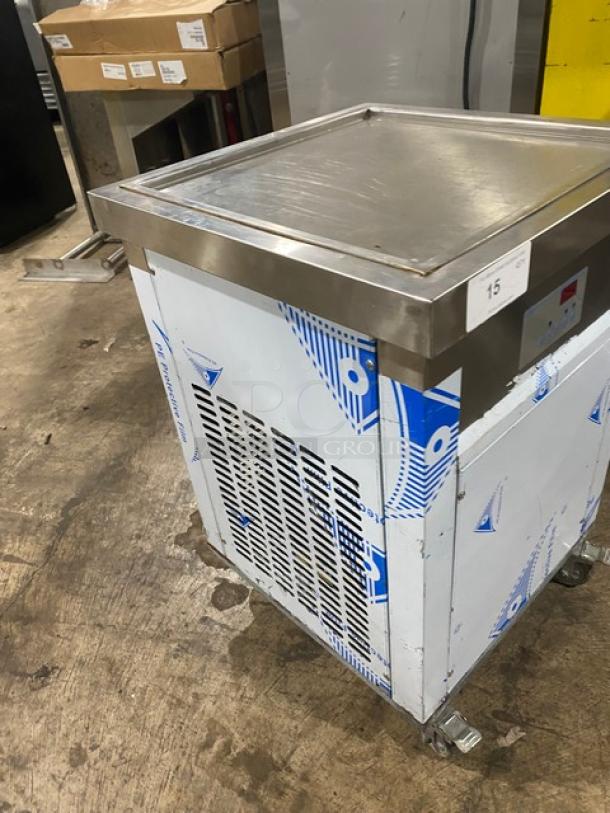 Commercial stainless steel ice cream freezer with protective wrap, on casters. Minor wear visible. Label marked "15."