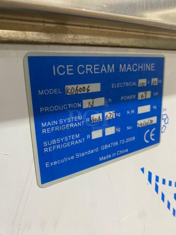 Blue label on ice cream machine. Model KO6006, 110V, 0.9KW power, R404A refrigerant. Made in China. Production: 1L/h.