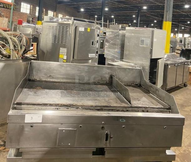 Stainless steel commercial griddle with dual grease channels, used condition, visible wear. Ideal for large kitchen setups.