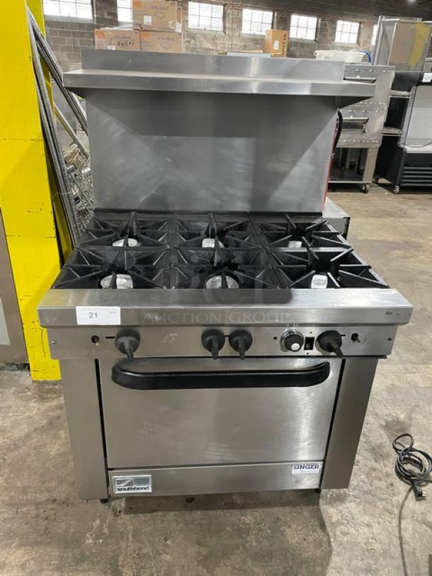Commercial Vulcan stove with six burners and an oven, stainless steel, shows minimal wear. Labeled Singer, model number visible.