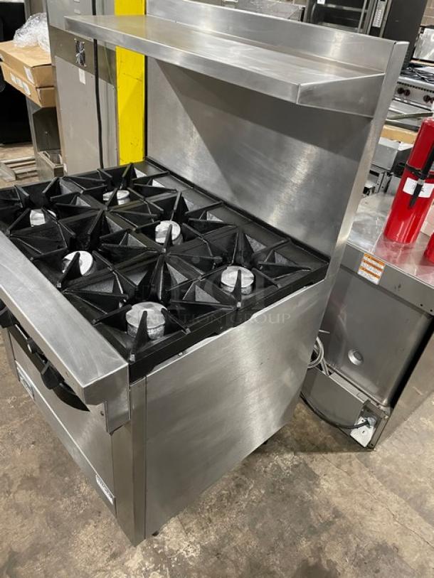 Stainless steel commercial gas stove with six burners and overhead shelf. Used condition, durable cast-iron grates.