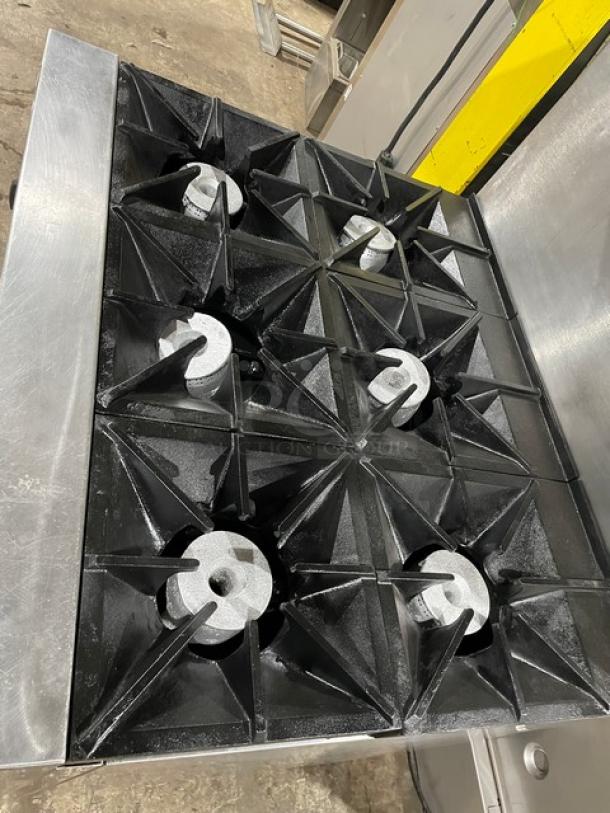 Commercial six-burner gas stove with cast iron grates, stainless steel finish, in good used condition.