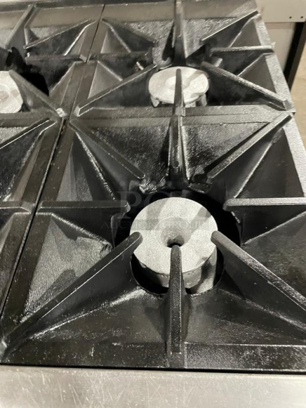 Commercial gas stove with four cast iron burners in good condition, showing robust design and minimal wear.