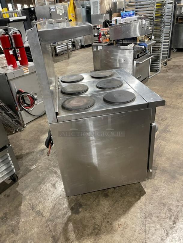 Stainless steel commercial stove with four round hot plates. Used, good condition. Ideal for industrial kitchen use.