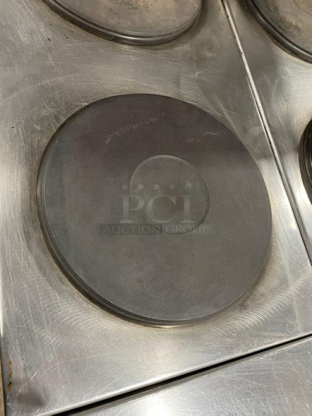 Stainless steel electric stove top with round, black solid disk heating element, showing minor wear marks.