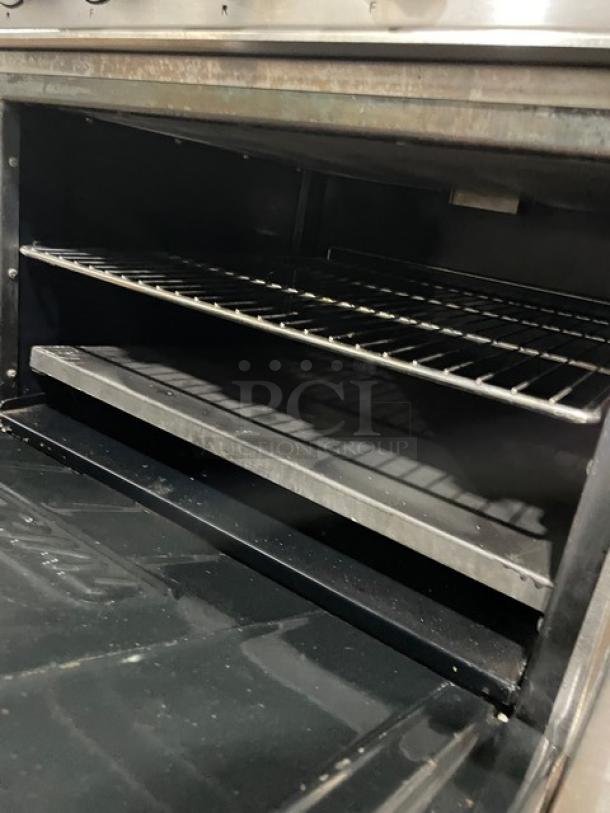 Industrial metal oven interior with two black racks, showing signs of wear and discoloration, suitable for commercial use.