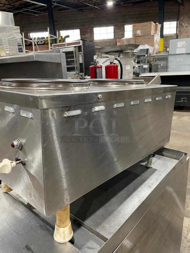 Stainless steel commercial soup warmer. Features dial controls and lid. Shows light wear. Ideal for restaurant use.