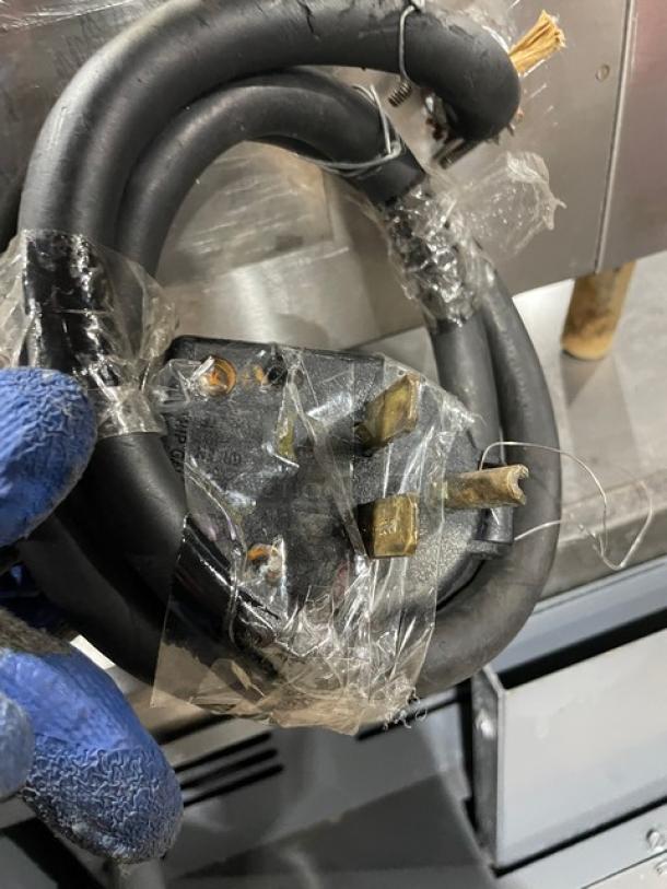Heavy-duty electrical power cord with three-prong plug, wrapped in protective plastic, slightly frayed, suited for appliances.