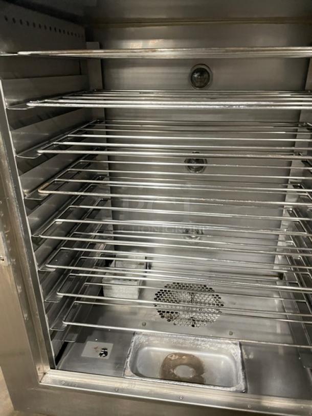 Stainless steel industrial oven with multiple wire racks. Clean interior, visible ventilation holes, used condition but well-maintained.