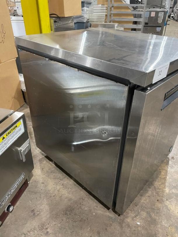 Stainless steel undercounter refrigerator, used condition with visible dents, labeled with "32", commercial grade features.