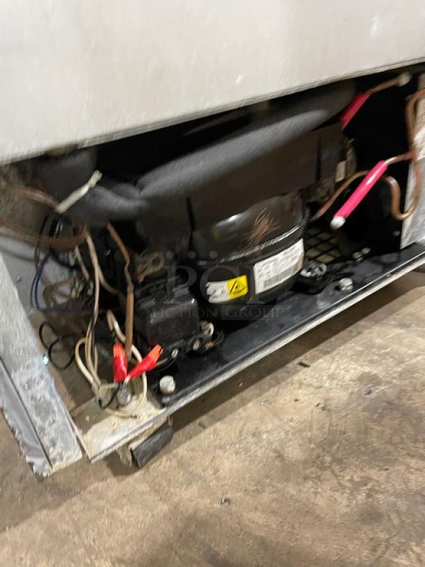 Refrigeration unit compressor, showing wires and connections, in used condition with visible label and warning symbol.