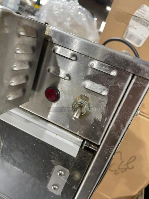 Vintage metal toaster with toggle switch and red indicator light, showing visible wear. Plug attached; no brand markings.