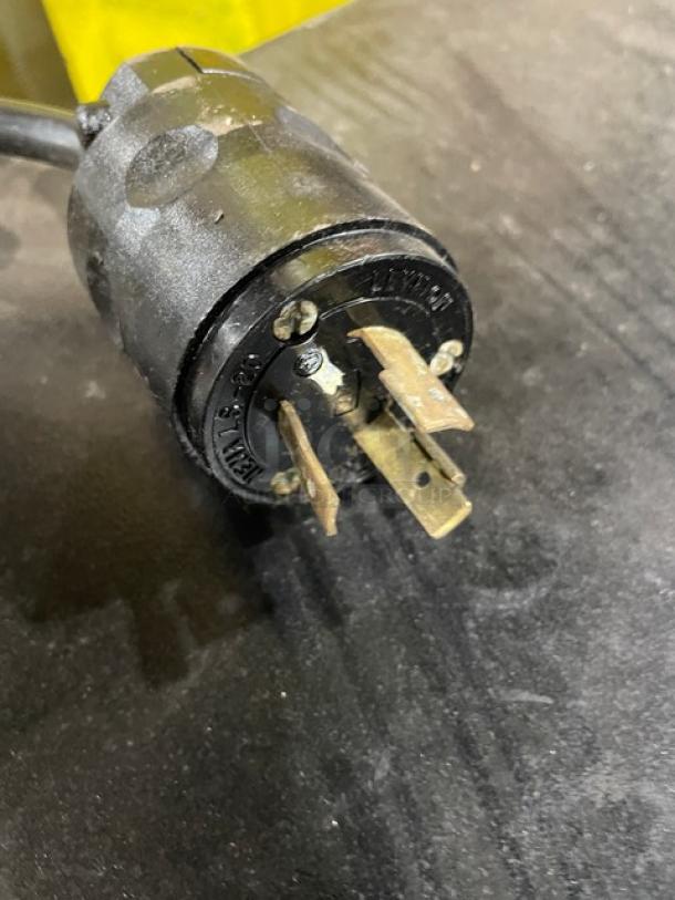 Heavy-duty electrical plug with three prongs, black casing, and visible brand marking, in used condition.